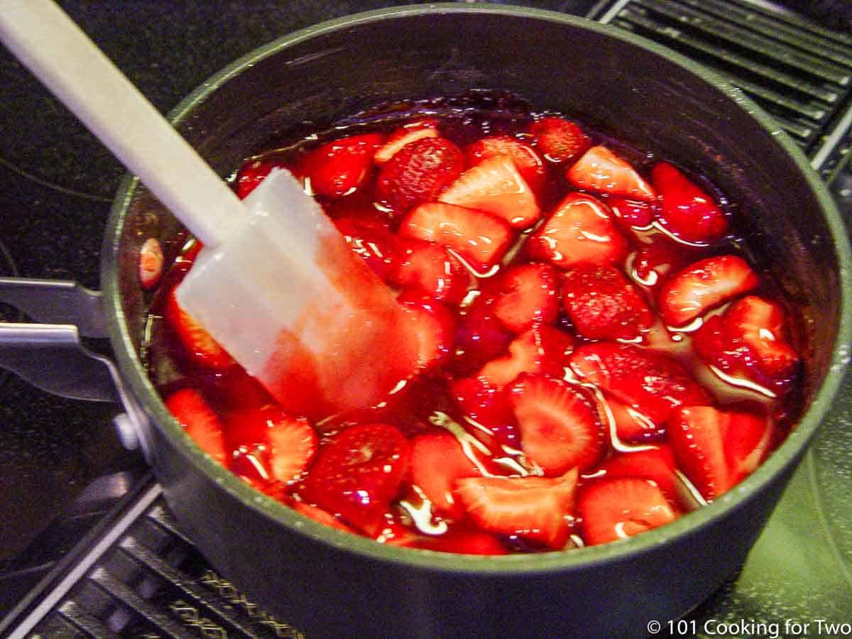 mixing strawberries into coating in saucepan