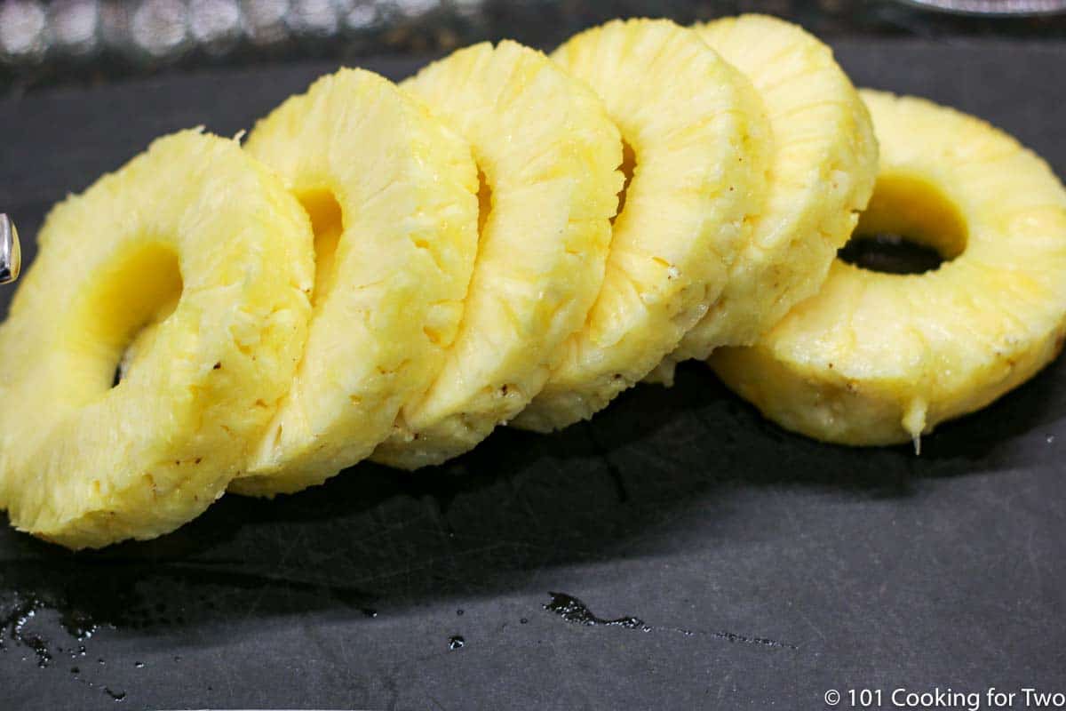 pineapple cut into slices on black board