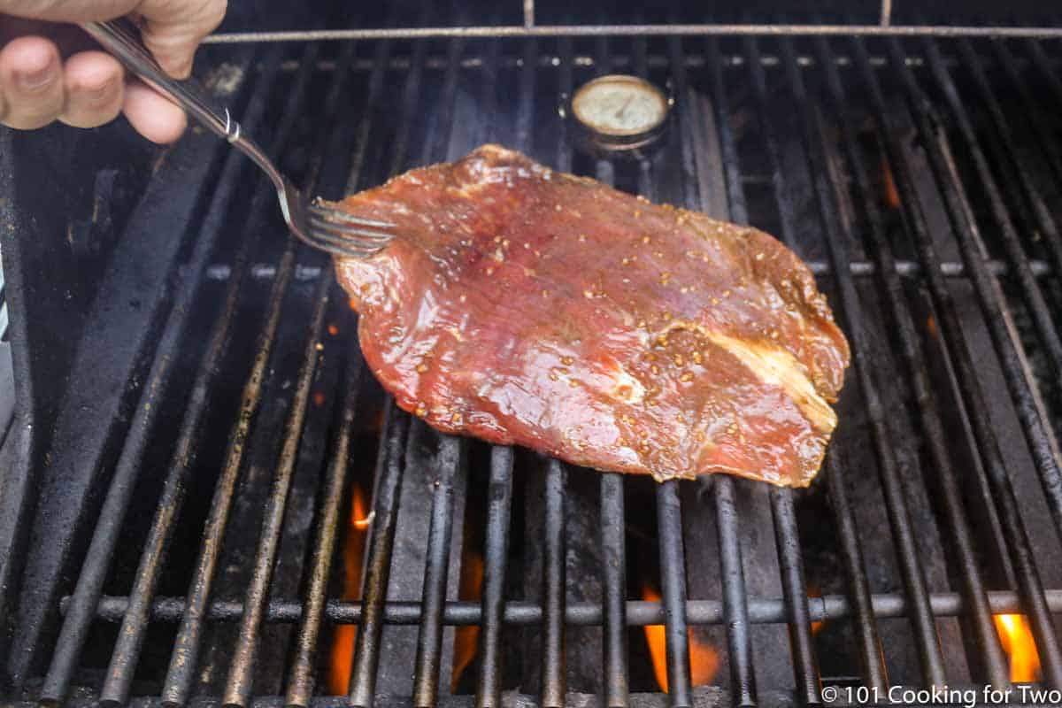 placing flank steak on grill.