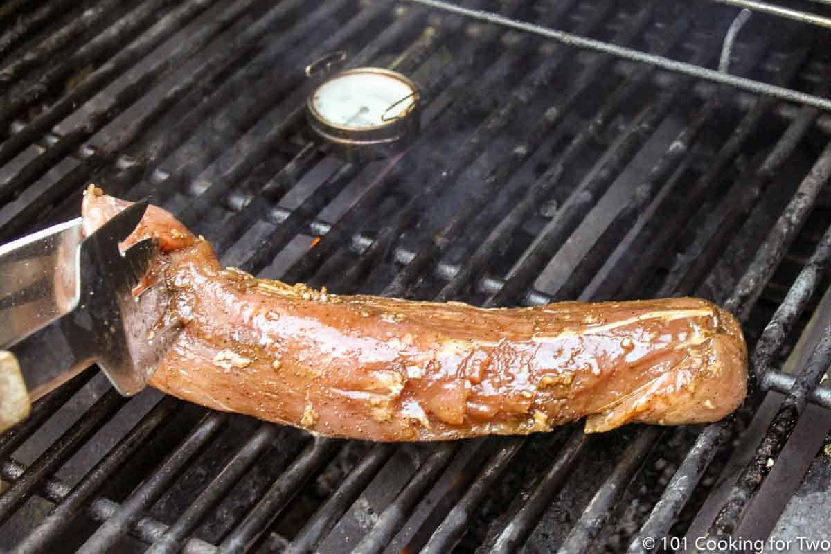 Placing pork tenderloin on grill surface.