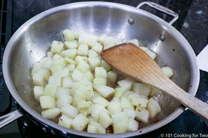 potatoes in the frying pan with wooden spoon