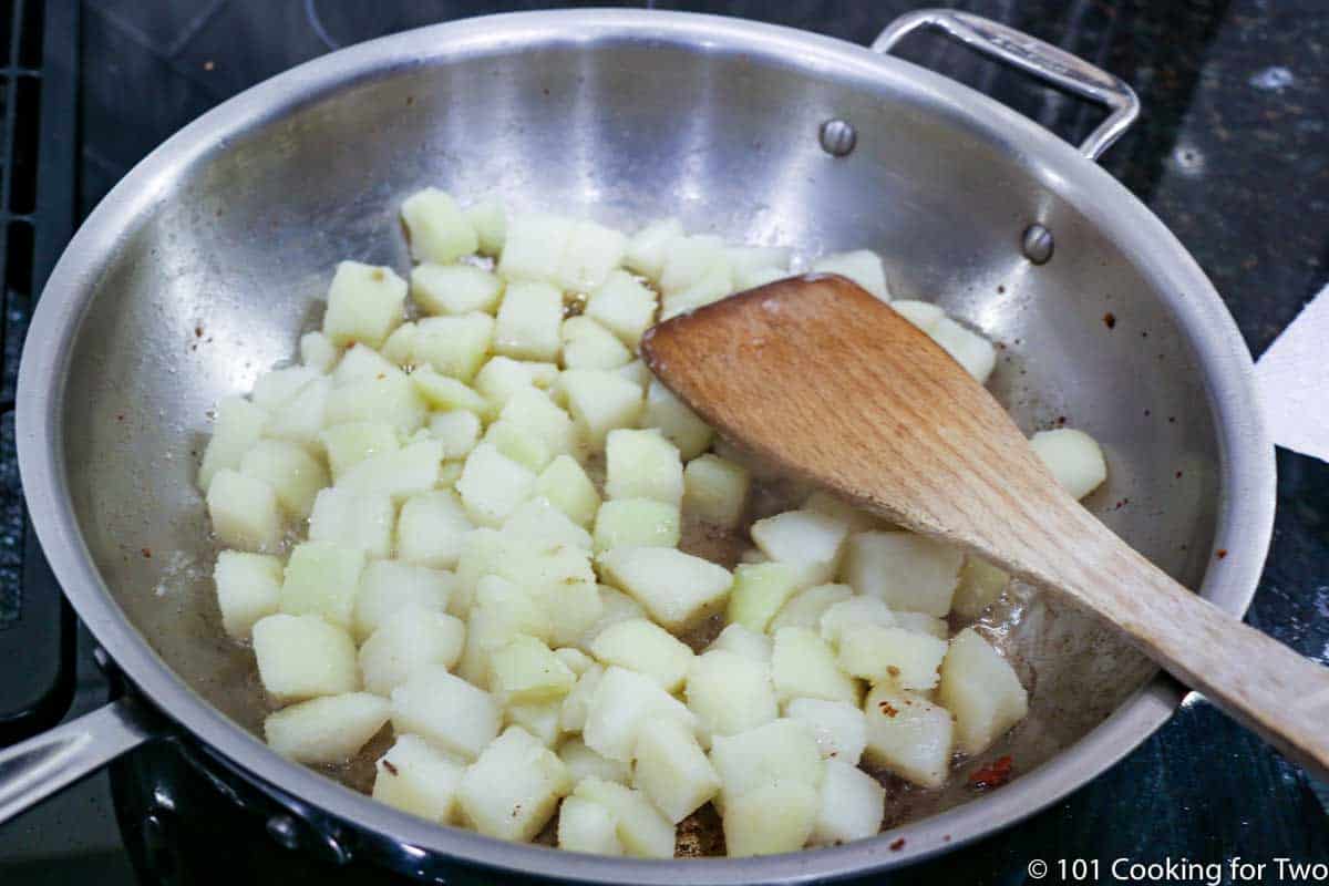 potatoes in the frying pan with wooden spoon.