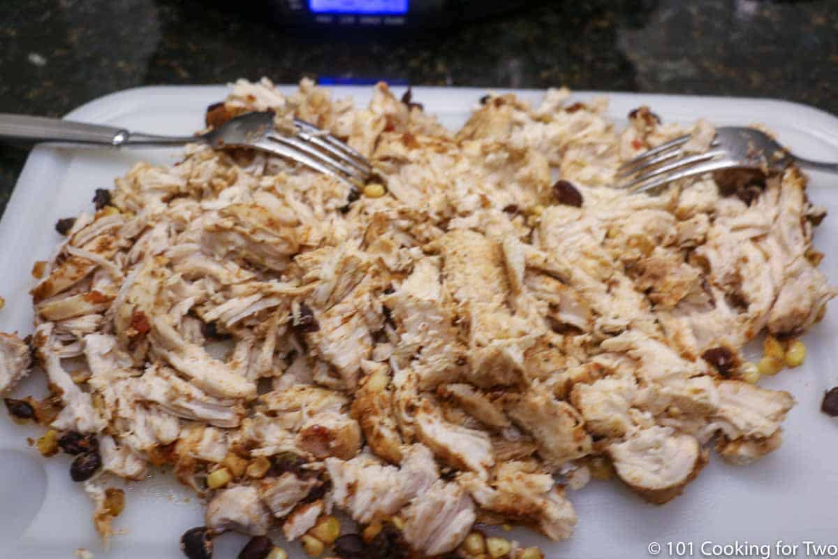 shredding cooked chicken on white board
