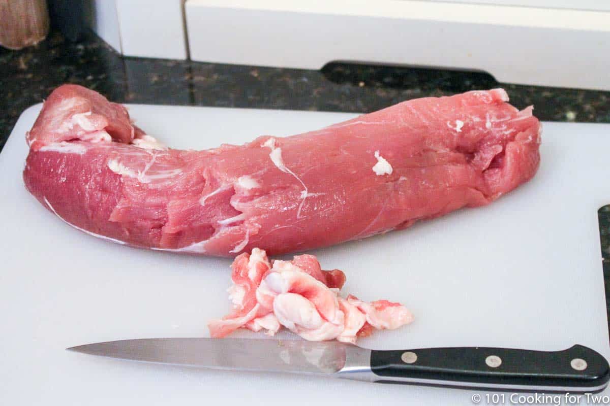 trimmed pork tenderloin on white board.