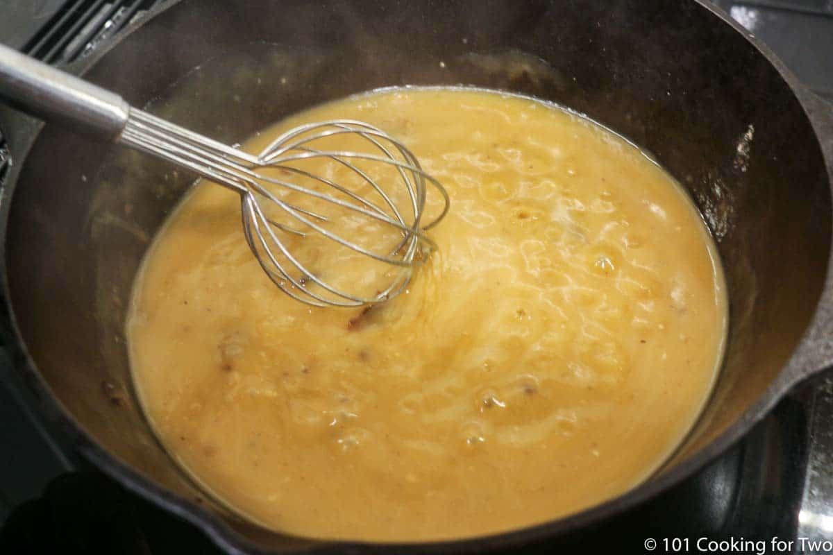 whisking gravy in cast iron pan.