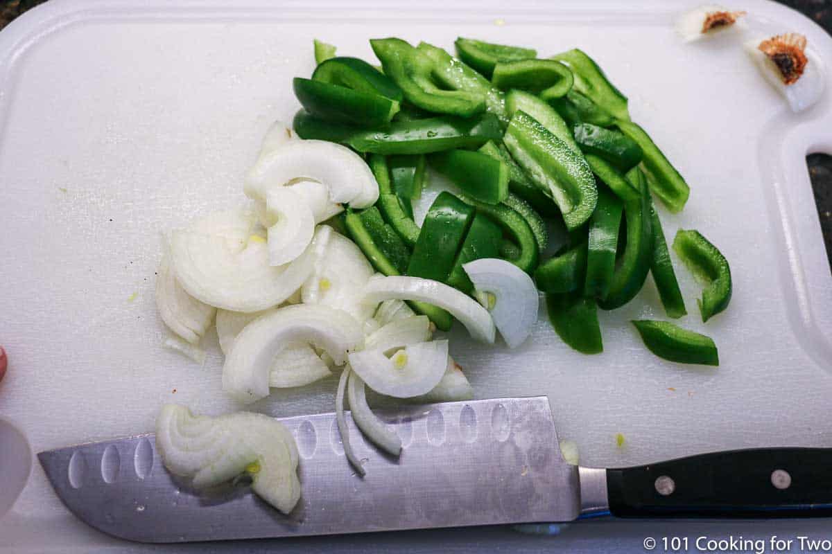 Chopped pepper and onion on white board.