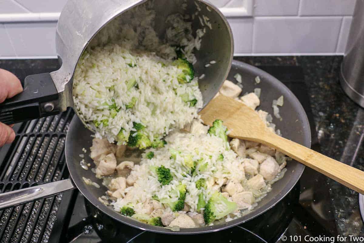 adding cooked rice and broccoli to cooked chicken in fry pan