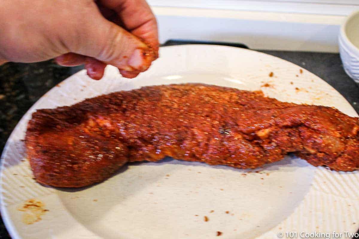 adding some more rub to tenderloin on white plate