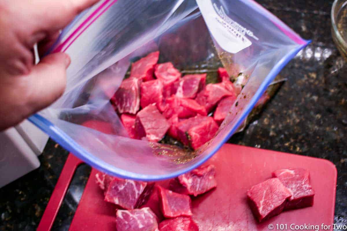 adding steak to bag with marinade.