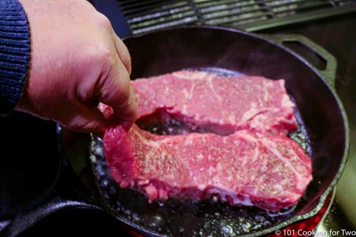 adding steaks to hot skillet