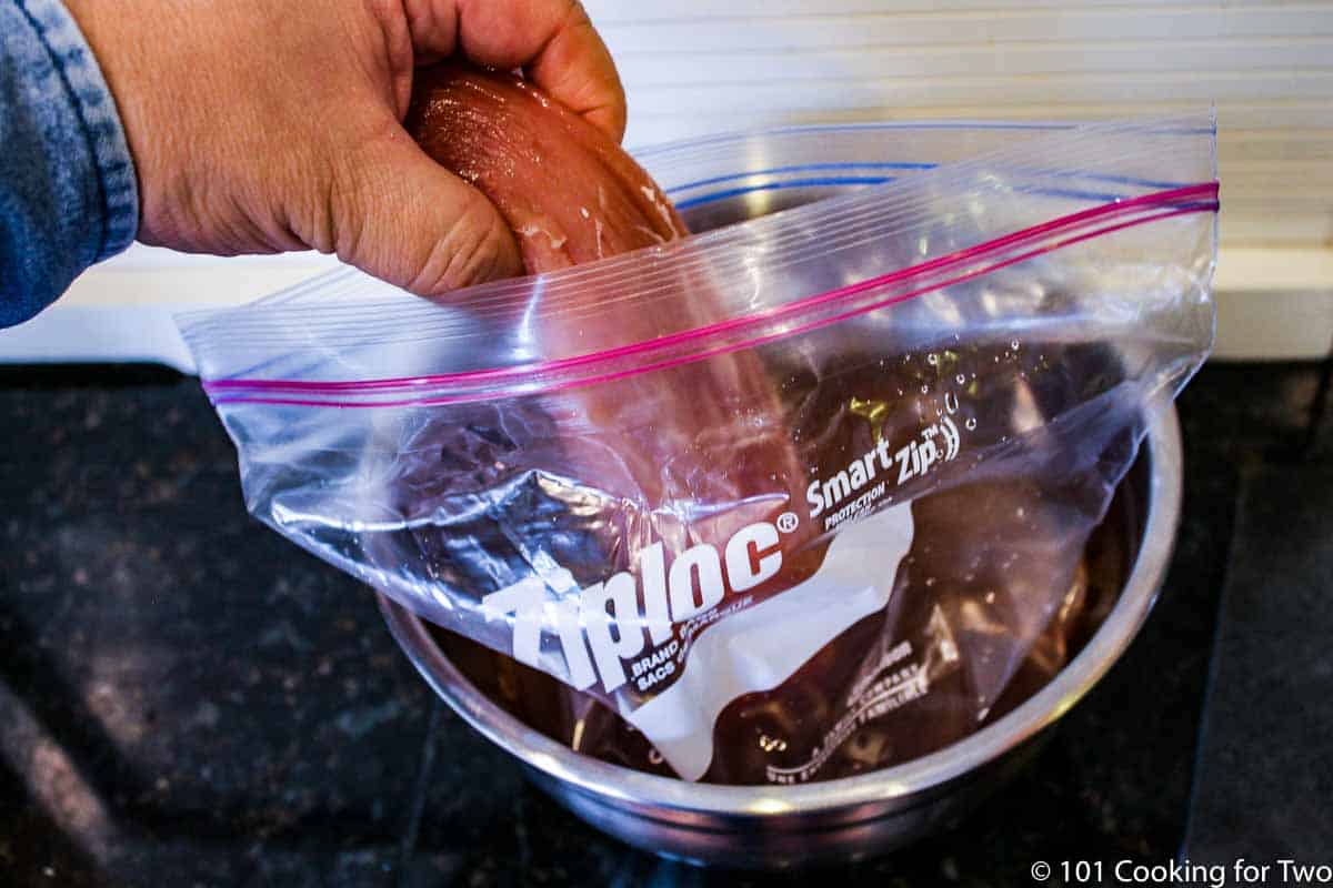 adding the pork tenderloin to the bag with brine