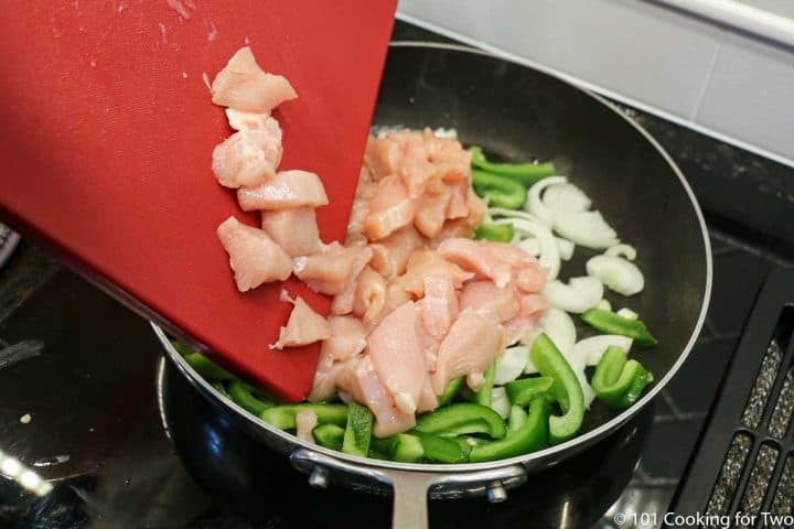 adding trimmed chicken to pan with pepper and onion