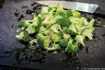 chopped broccoli on black board with knife