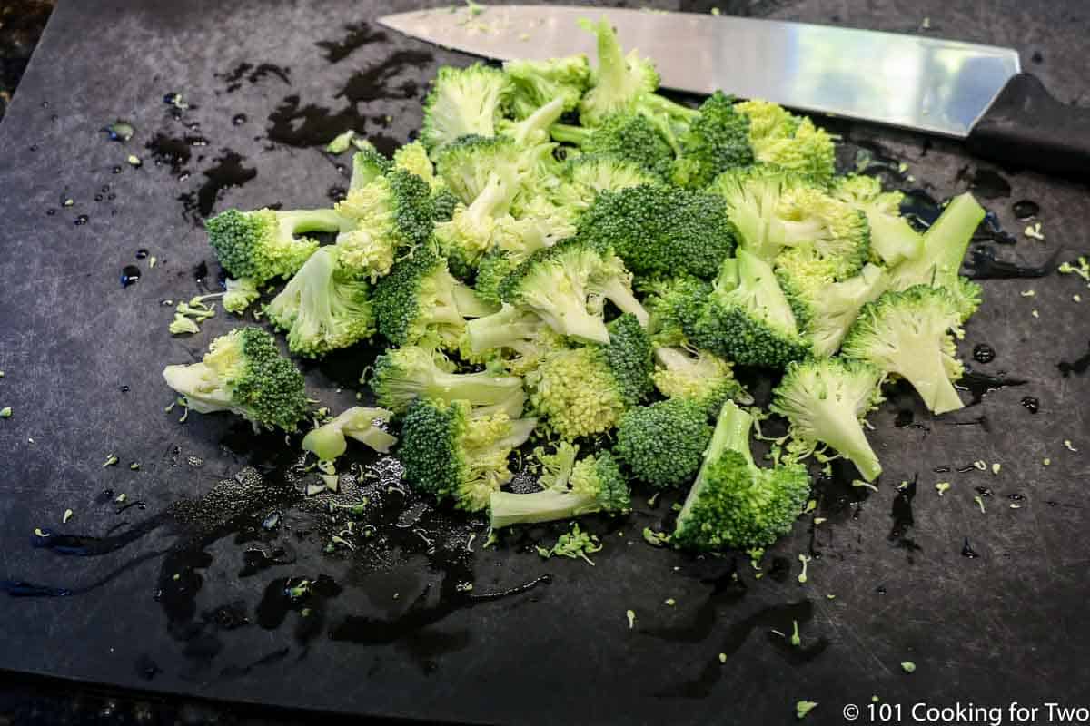 chopped broccoli on black board with knife.