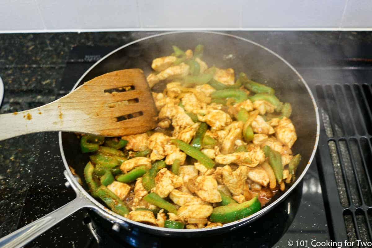 cooking chicken and vegetables in fry pan.