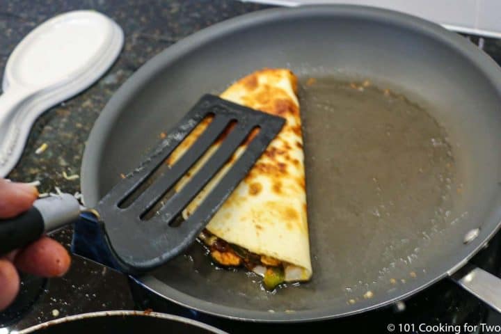 folding half the tortilla on the meat in a skillet