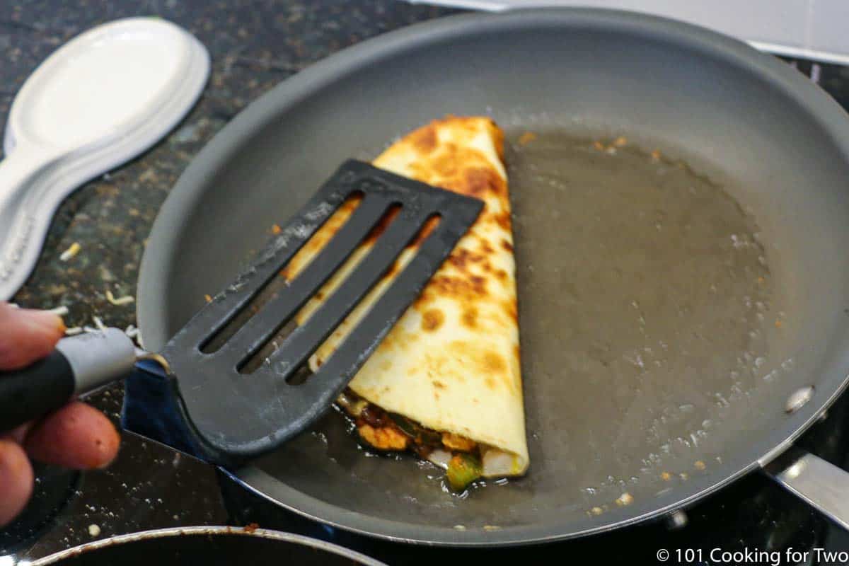 folding half the tortilla on the meat in a skillet.