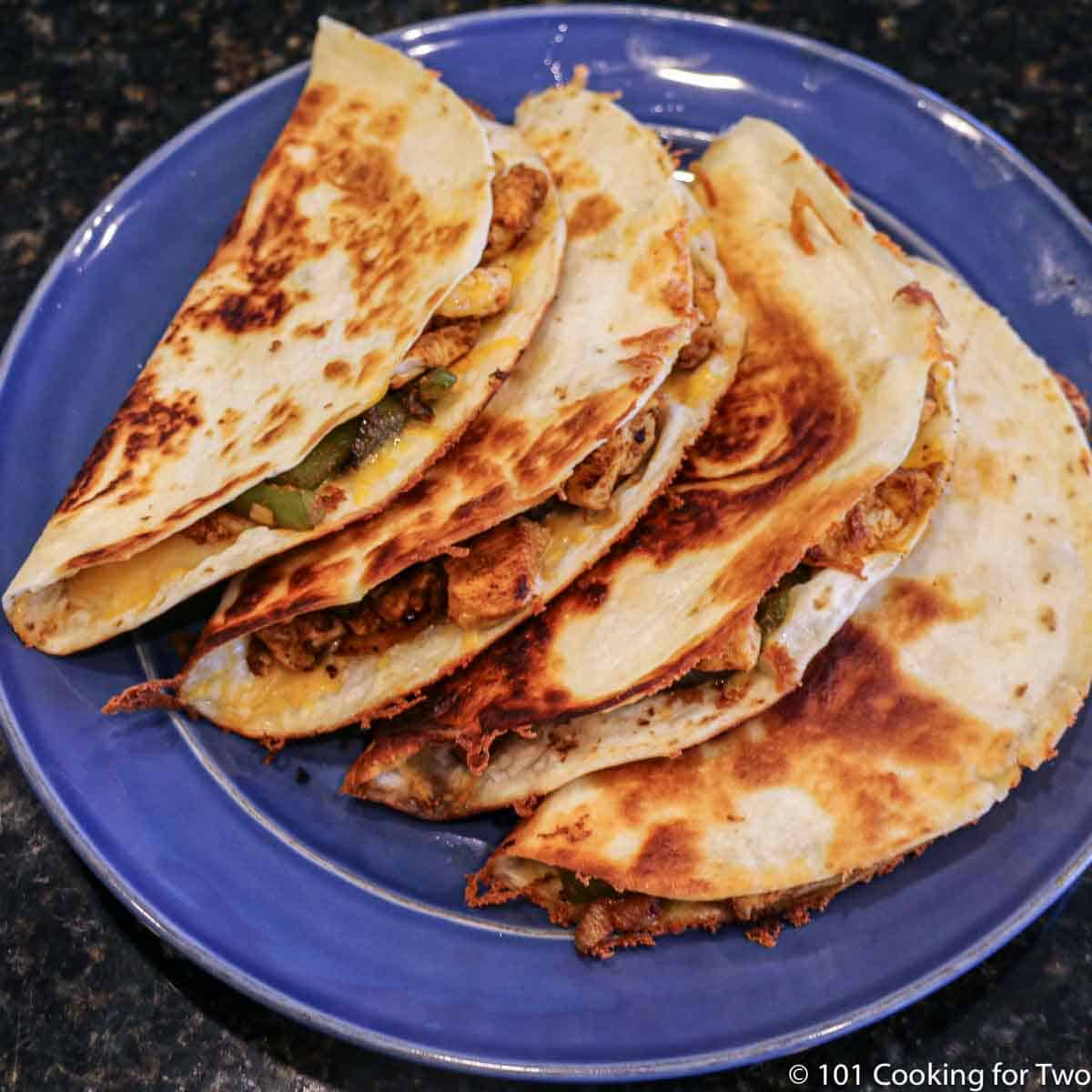 four fajita quesadillas on a blue plate.