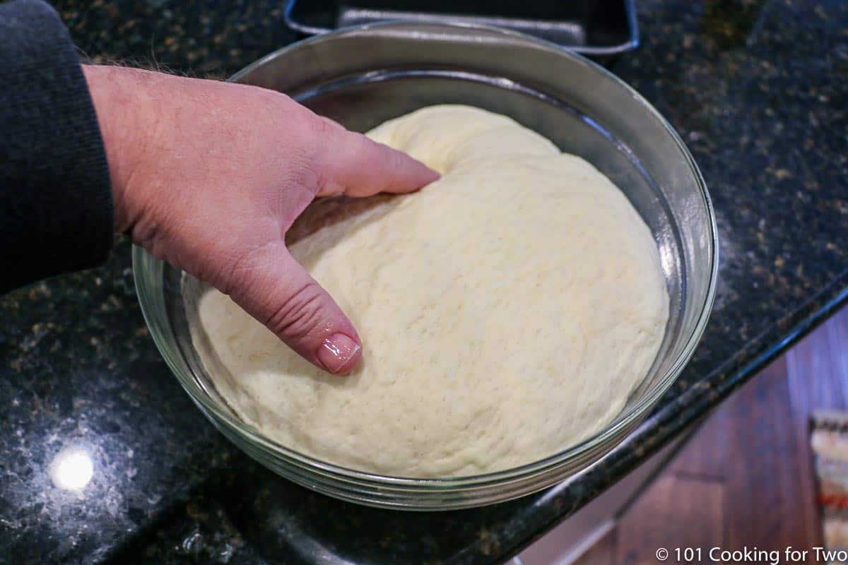 raised dough in a glass bowl