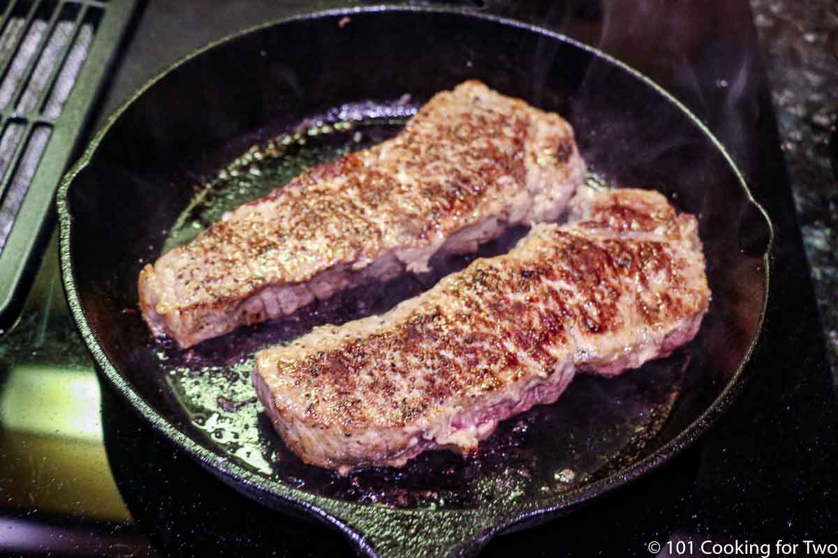 seared steaks in a black skillet.