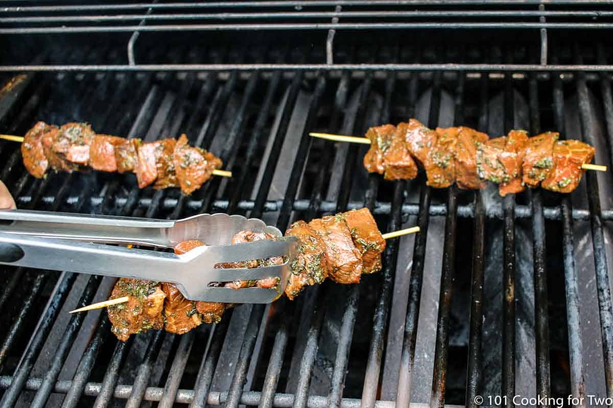 steak on skewers on grill grate.