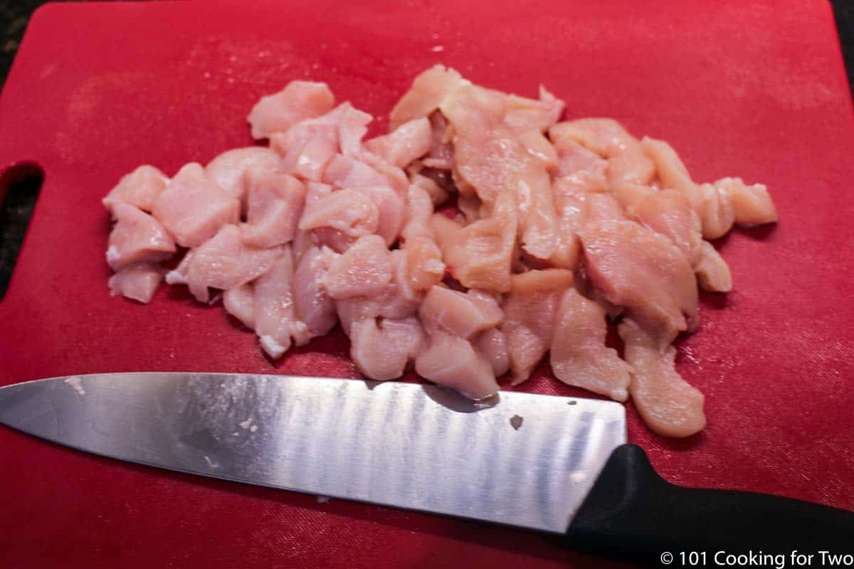 trimmed chicken on red board.