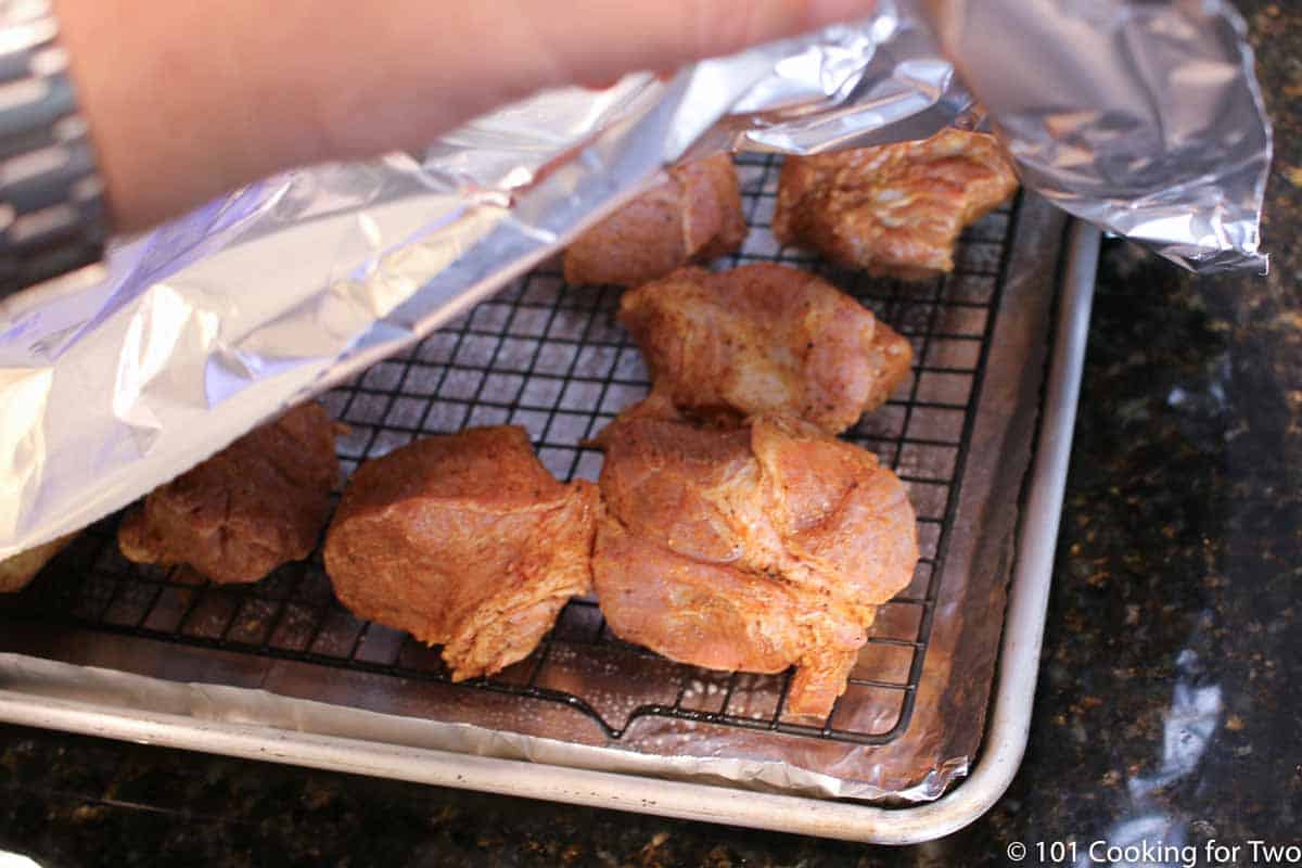 Covering tray of raw pork with foil.