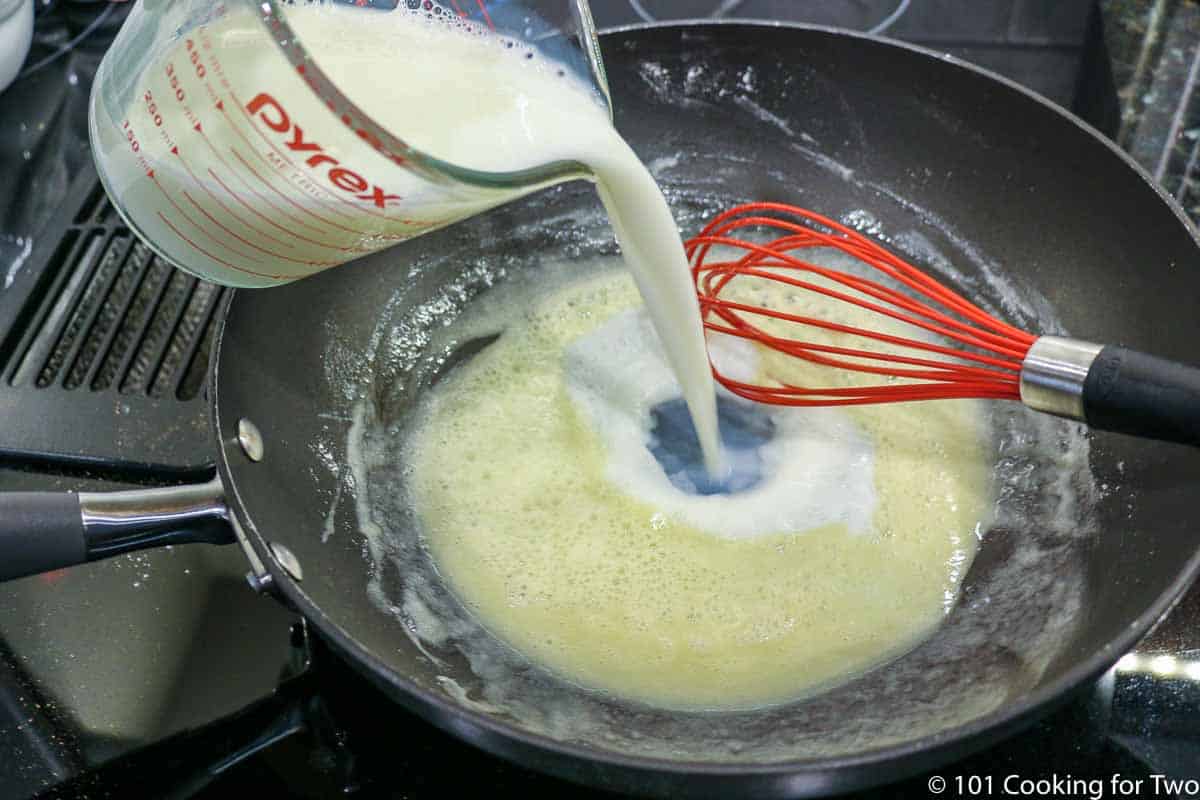 adding milk to pan with a roux and whisk