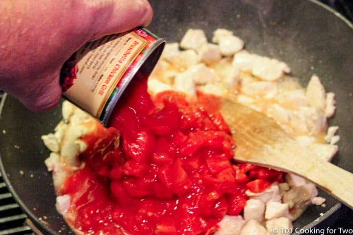 adding tomato sauce into pan with cooked chicken