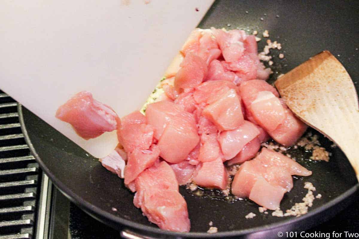 adding trimmed chicken to fry pan.