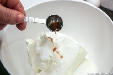 adding vanilla to bowl with sugar and cream cheese