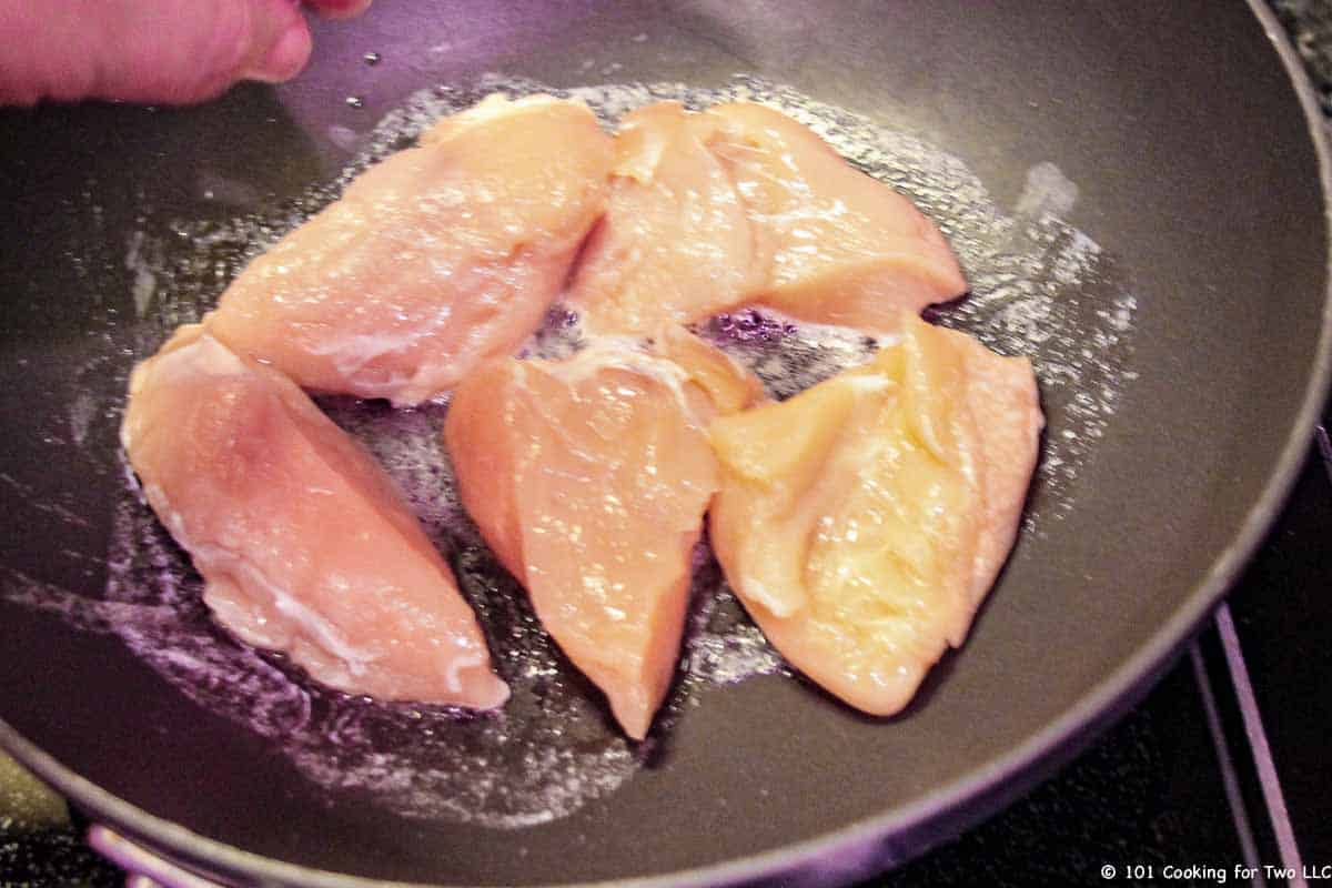 frying pieces of chicken in black pan