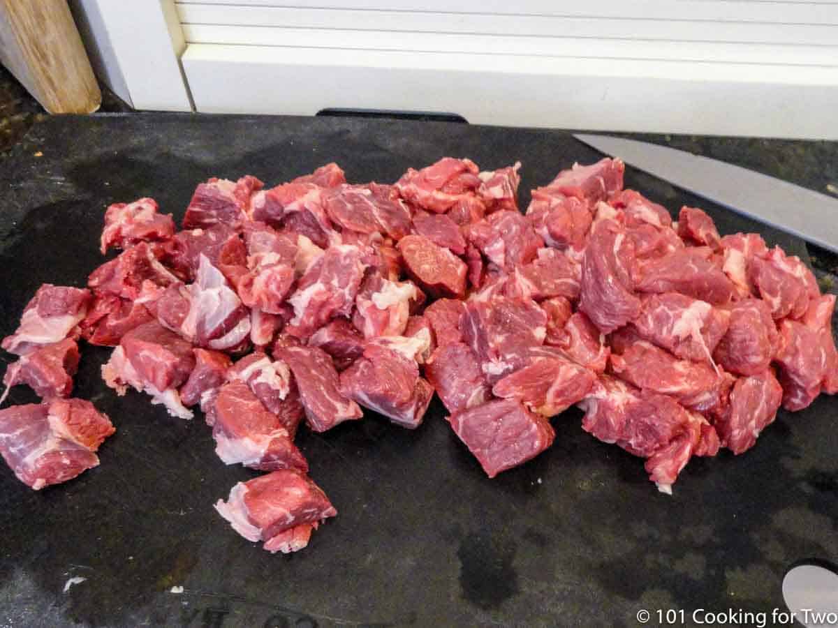 pile of trimmed beef in cubes on black board
