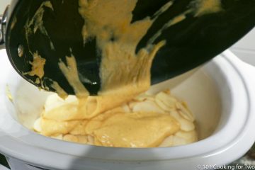 pouring cheese mixture onto the potatoes in a large crock pot