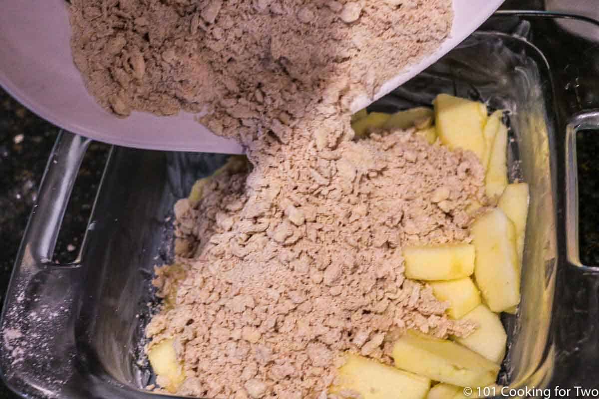 pouring topping on apple slices in baking dish
