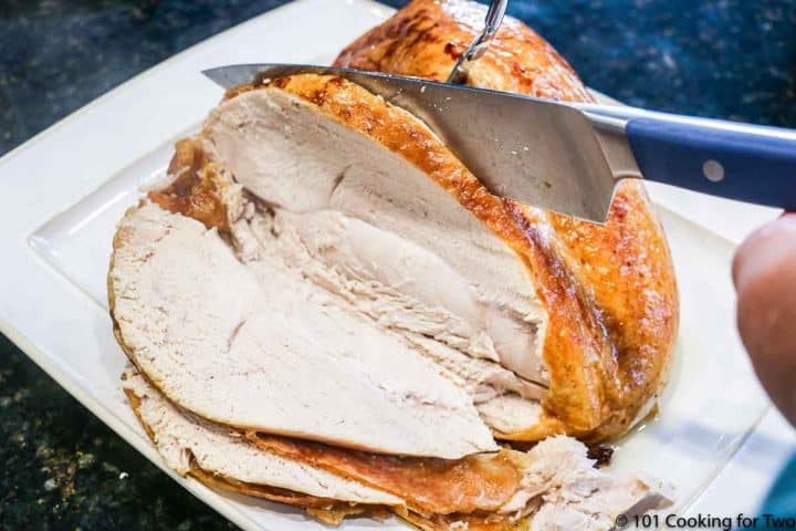 slicing a turkey breast on a white platter