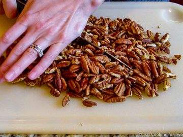 chopping pecans on whte board with knife