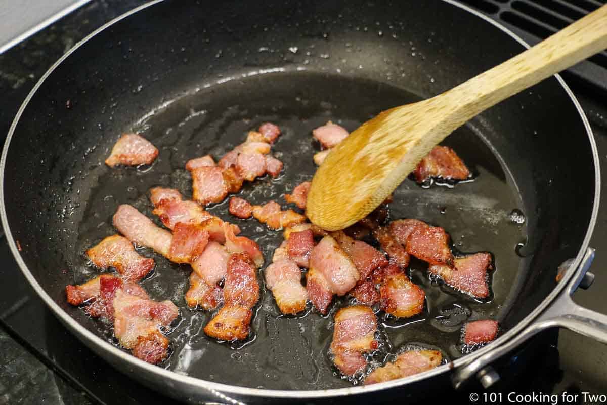 cooking cut up bacon in a fry pan.