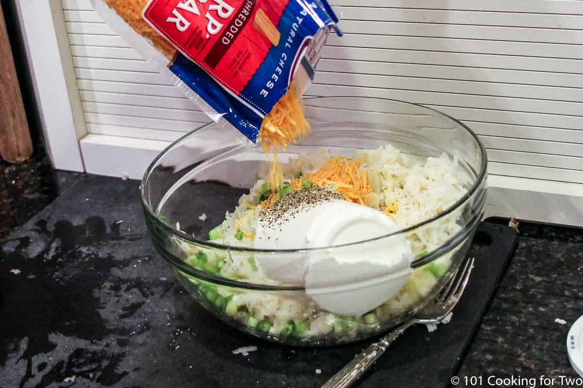 adding shredded cheese to mixing bowl with alll other ingredients.