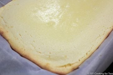 baked cheesecake bars in pan showing browning edge with shimming center