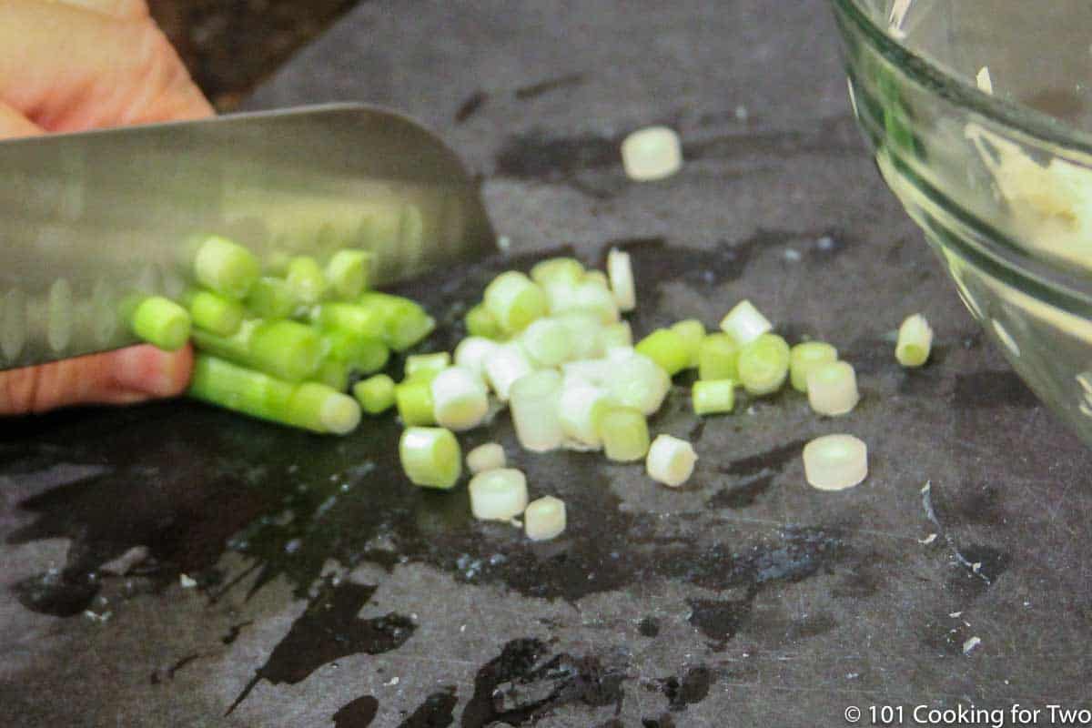 chopping green onions on black board