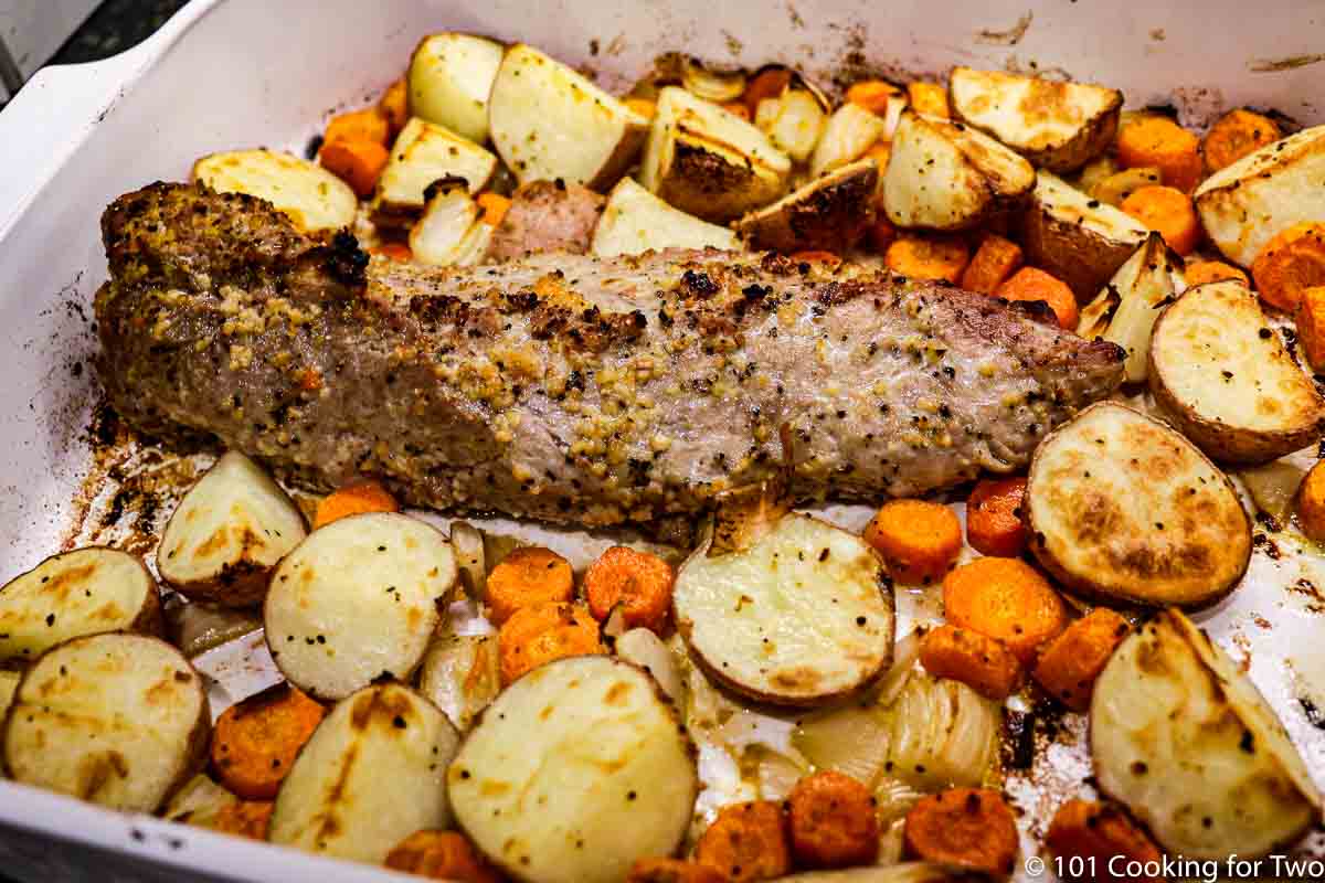cooked pork tenderloin with carrots and potatoes in baking dish