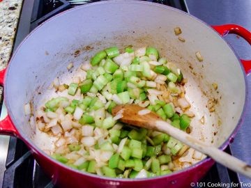 cooking celery and onion in a red Dutch oven