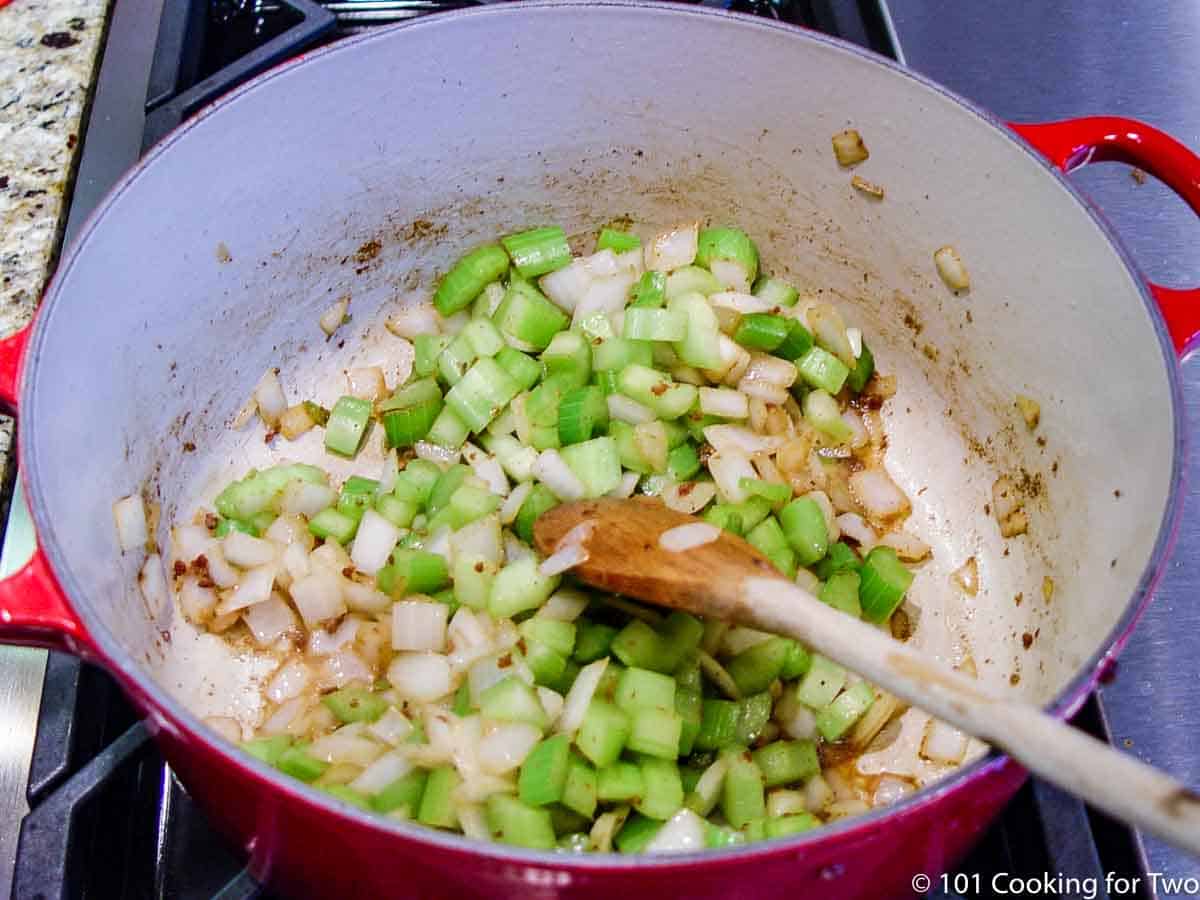 cooking celery and onion in a red Dutch oven.