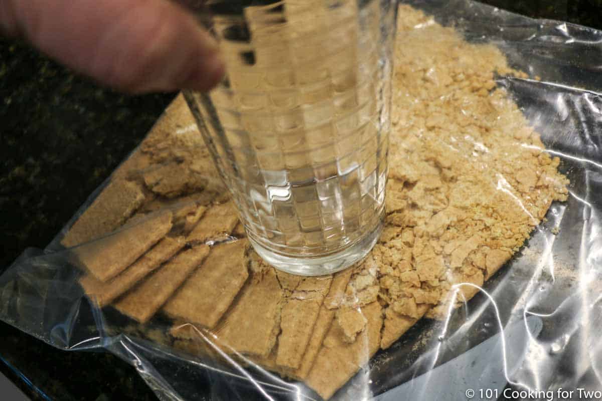 crushing graham crackers in bag with a glass.