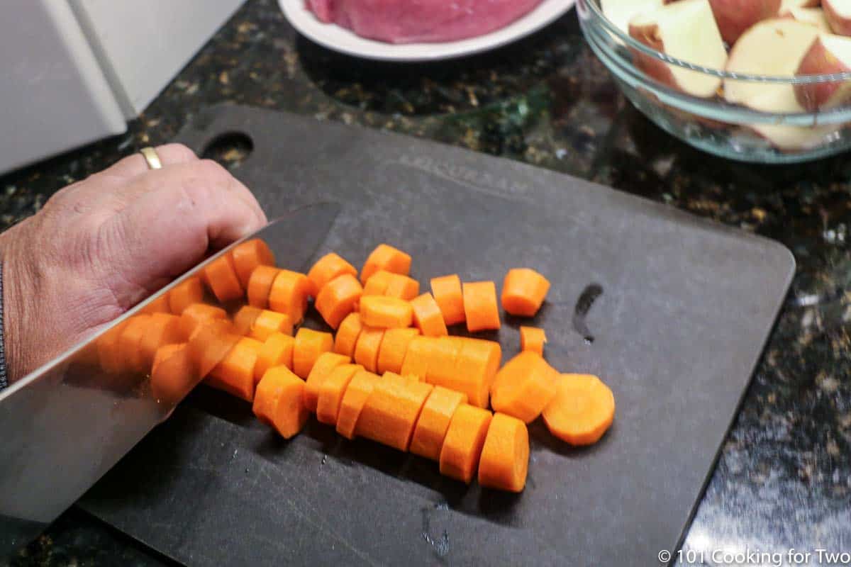 cutting up carrots on a black chopping board