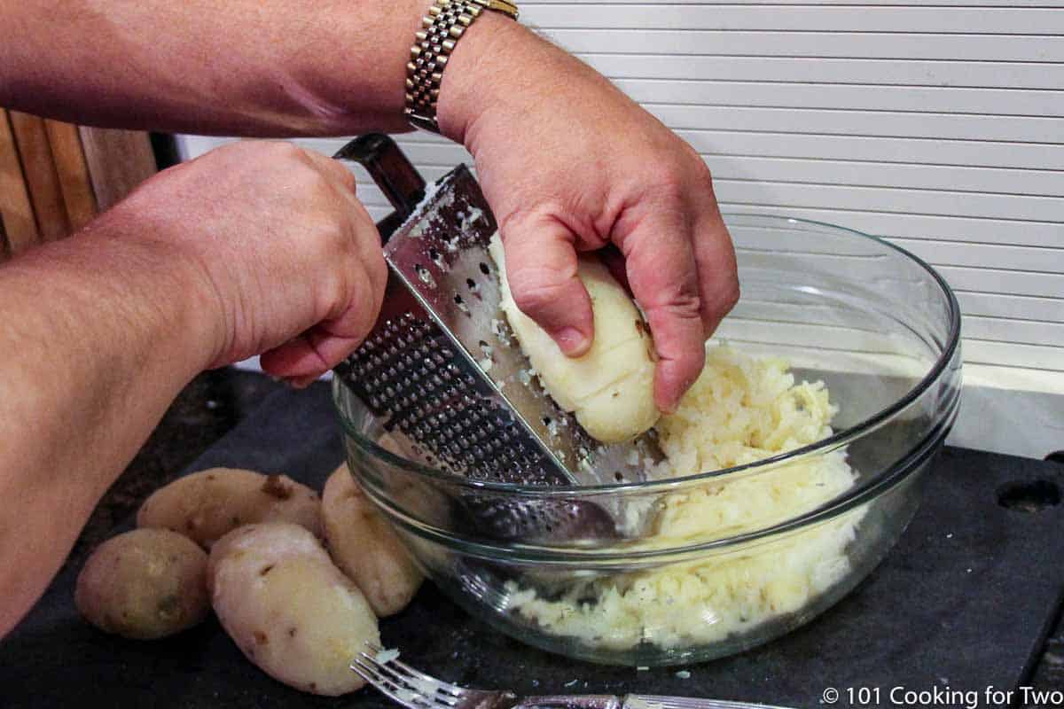 grating potatoes into large glass mixing bowl.