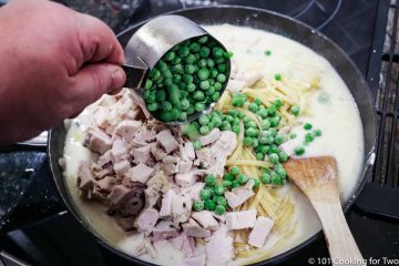 mixing in the turkey and peas to the pan with sauce and pasta