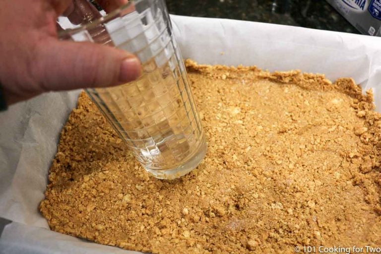 pressing crust into prepared pan with bottom of a glass