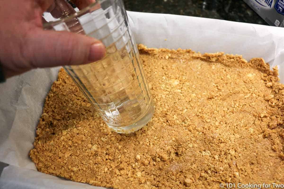 pressing crust into prepared pan with bottom of a glass.